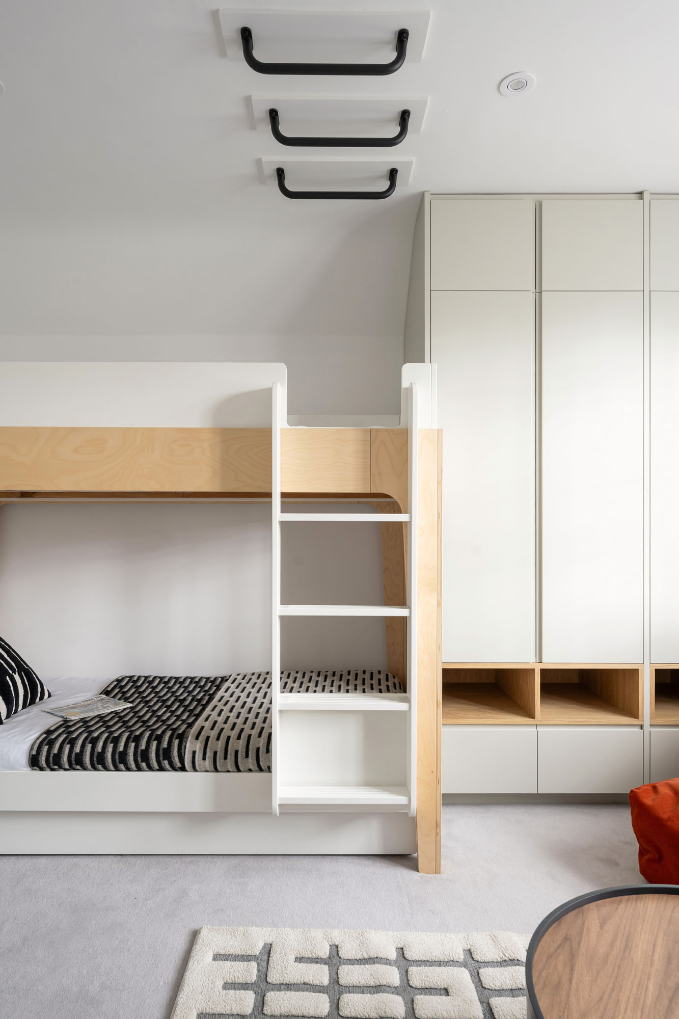 Funky Little Darlings neutral decor boys bedroom with Oeuf NYC bunk bed, bespoke wardrobes with oak display inserts and monochromatic bed linen and monkey bars across the ceiling.