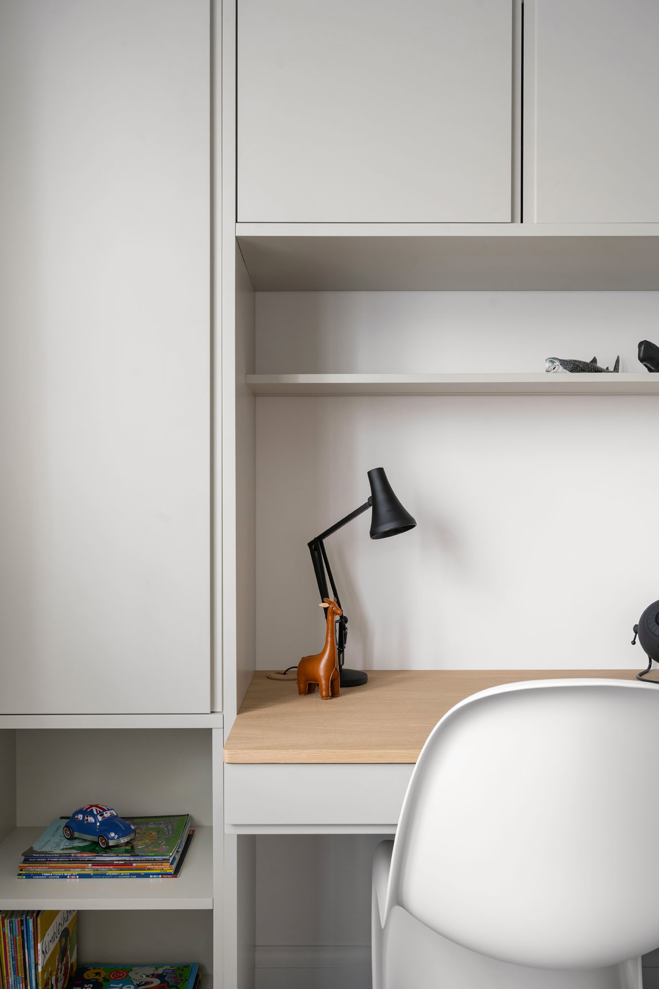 Boys neutral bedroom study area by Funky Little Darlings featuring an oak desk, shelves, Anglepoise lamp, and a white Verner Panton chair for a stylish and functional workspace.