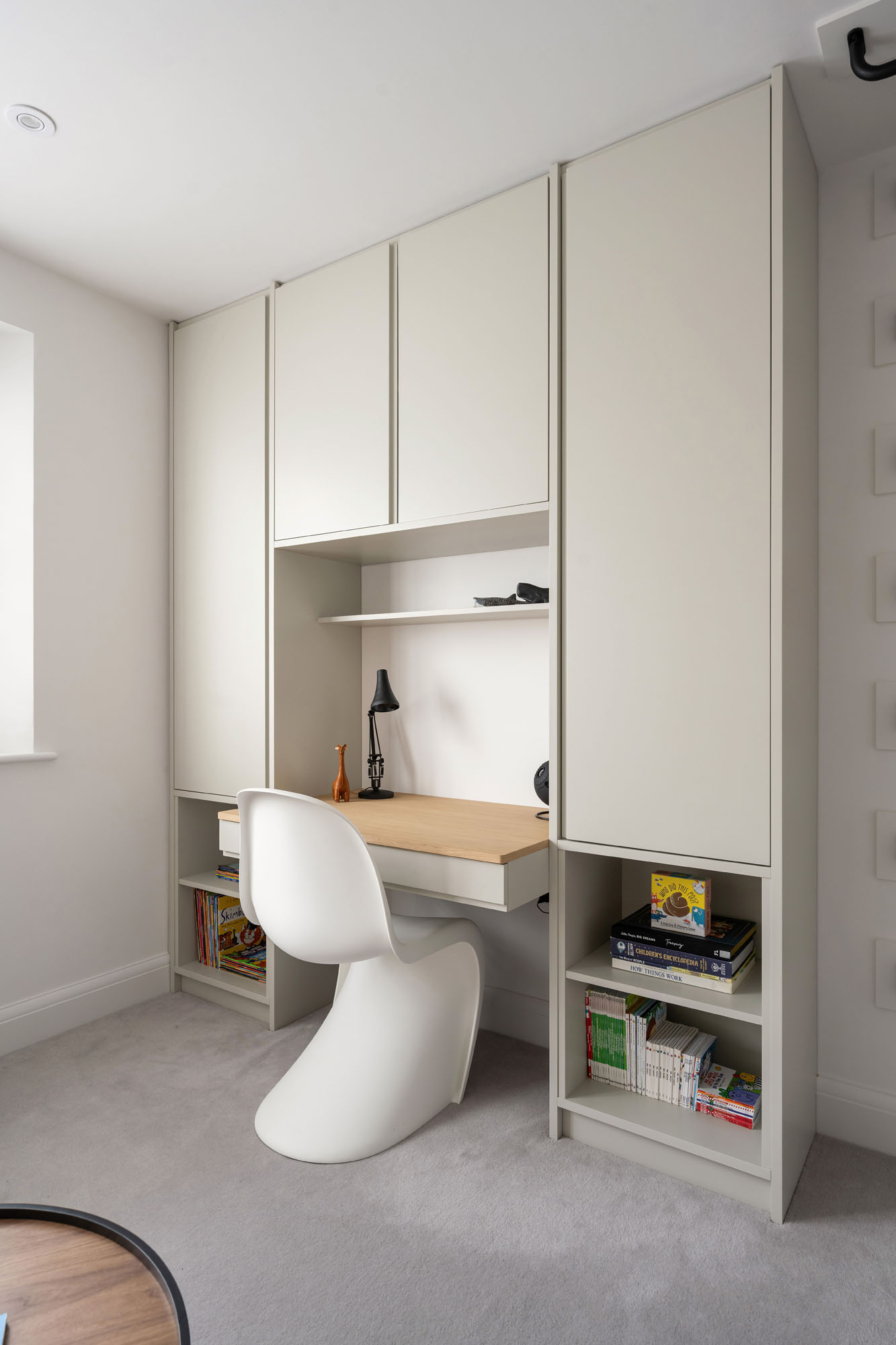 Modern boys bedroom study zone by Funky Little Darlings with oak desk, built-in storage display, and white Verner Panton chair for a stylish and functional workspace.