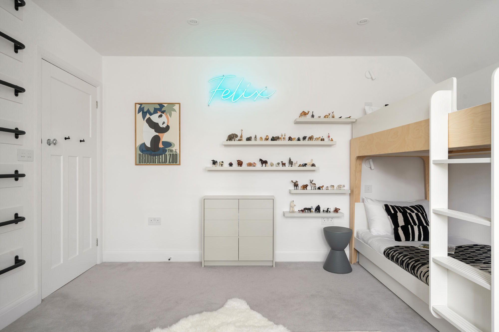 Amersham boys bedroom by Funky Little Darlings with Oeuf NYC bunk bed, wall mounted shelves with Schleich animals on  display, cupboard with hidden secret tunnel into siblings bedroom, custom neon name sign light and wall and ceiling mounted monkey bars.