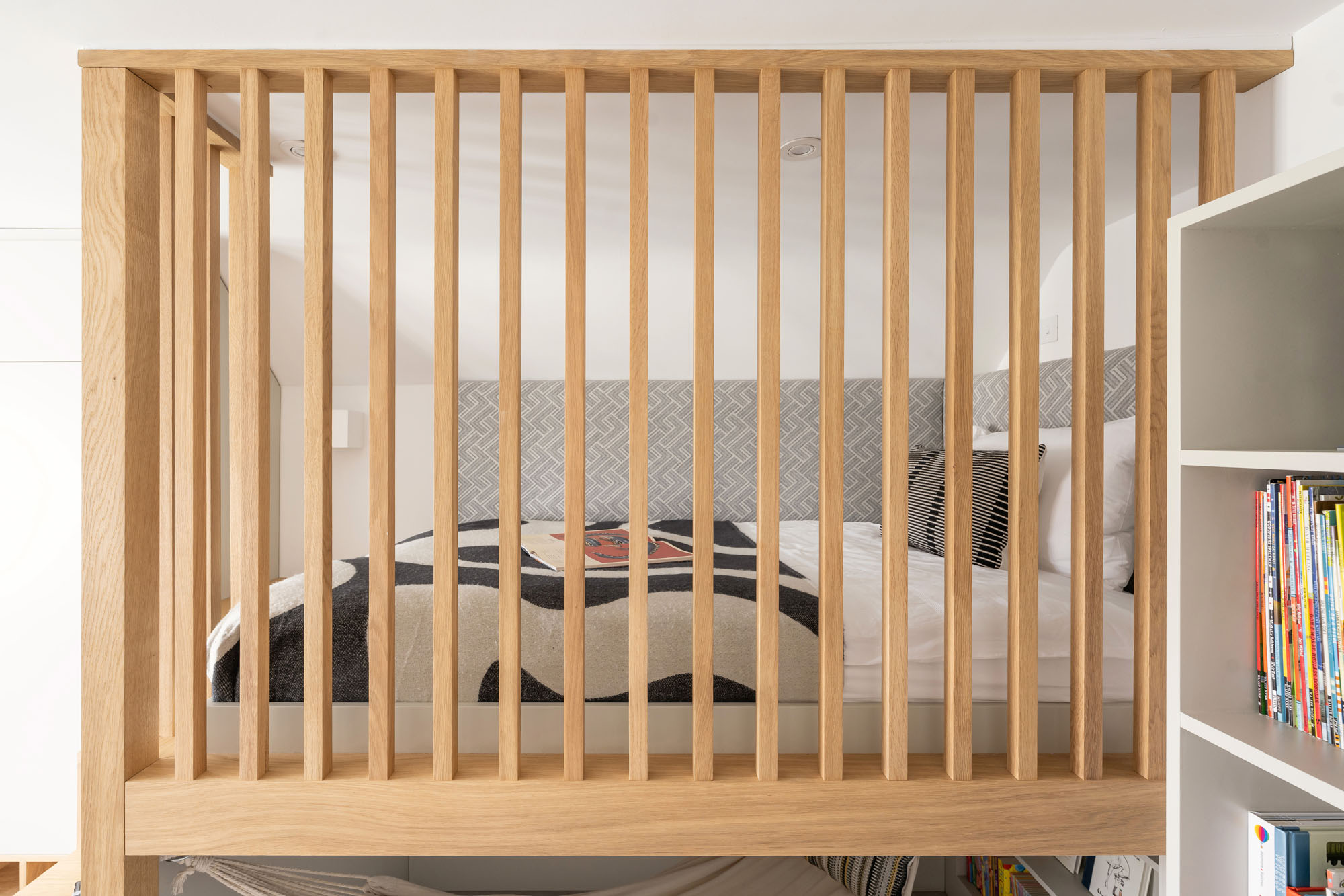 Funky Little Darlings custom boys bedroom in Amersham featuring view through natural oak safety bars to elevated bed platform in this stylish and safe kids room design.