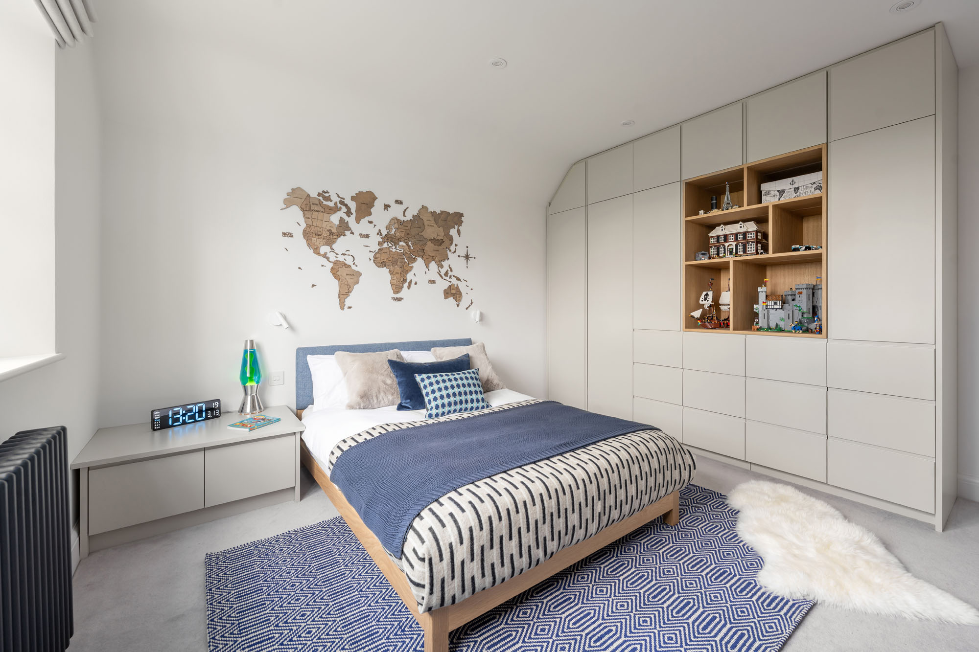 Stylish boy’s bedroom in Amersham featuring bespoke cabinetry, built-in wardrobes, and a decorative wooden world map, designed by Funky Little Darlings to blend functionality with playful, educational design.