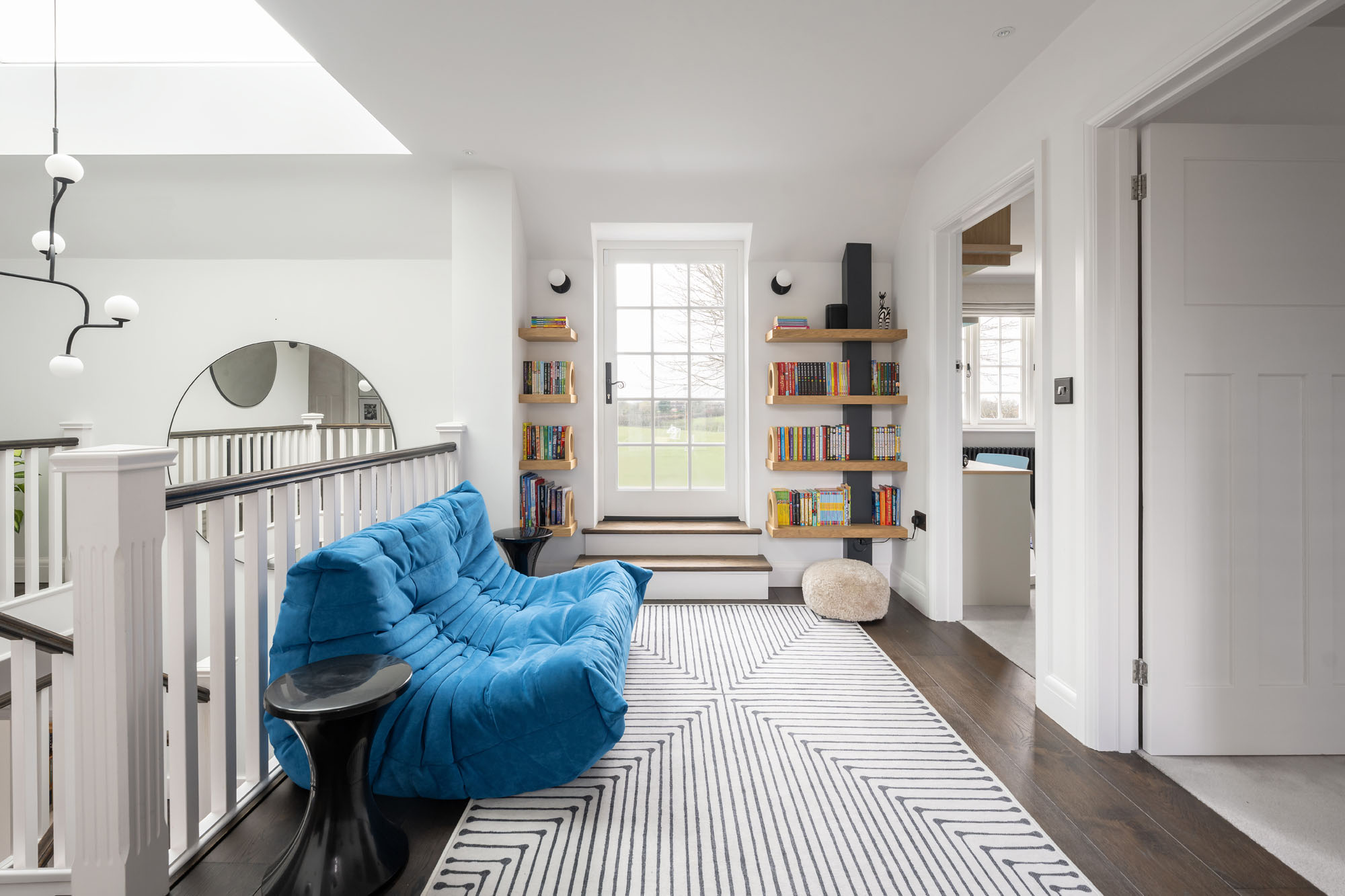 Stylish boys' hallway chill-out zone by Funky Little Darlings with a Togo sofa by Ligne Roset on a Jonathan Adler rug, a mini library for reading, and a study desk for homework designed for cosy, organised, modern family living.
