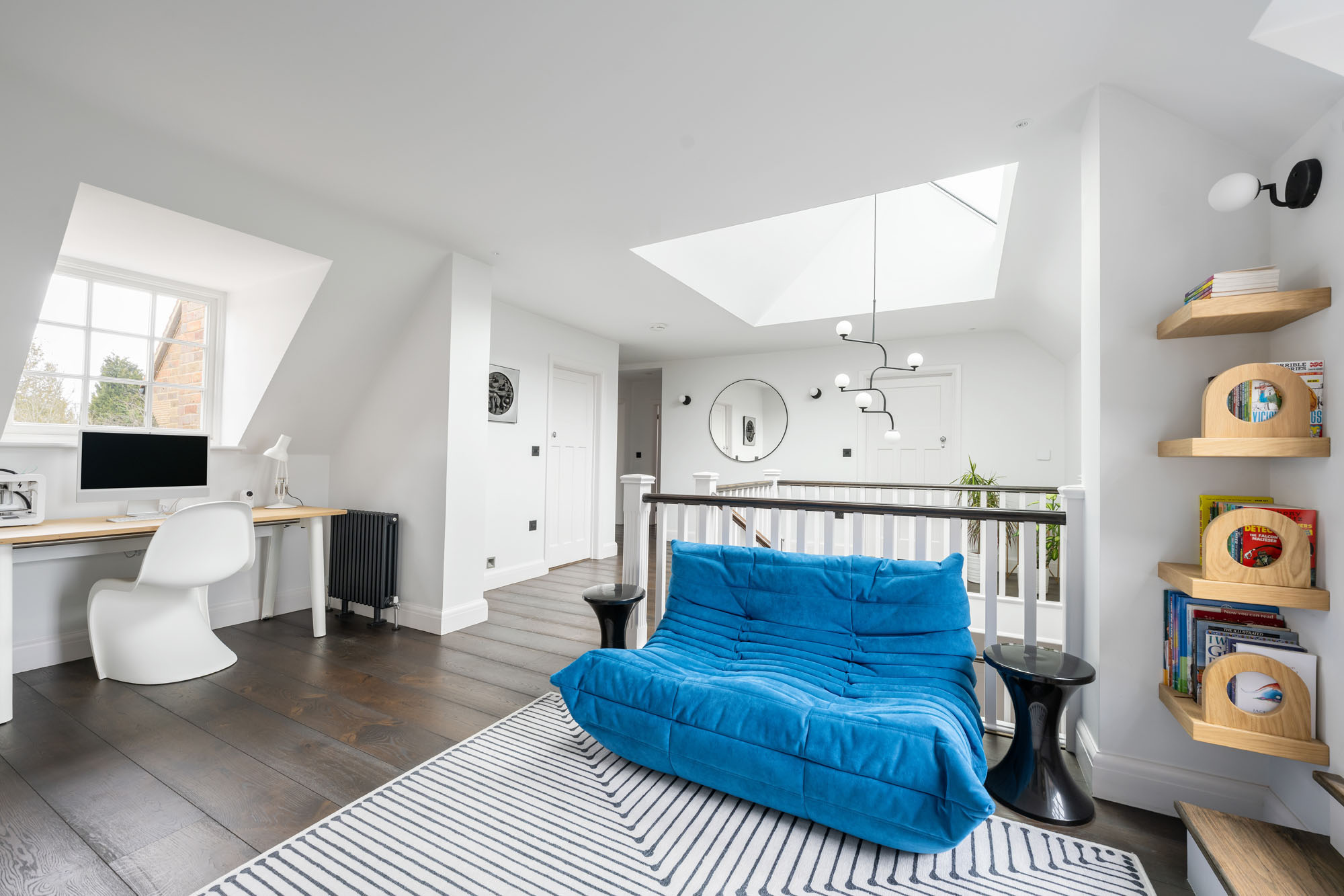 Stylish boys' hallway chill-out zone in Amersham by Funky Little Darlings, featuring a blue Togo sofa by Ligne Roset on a Jonathan Adler rug, mini library, study desk with white Panton chair designed for cosy, organised, modern family living.