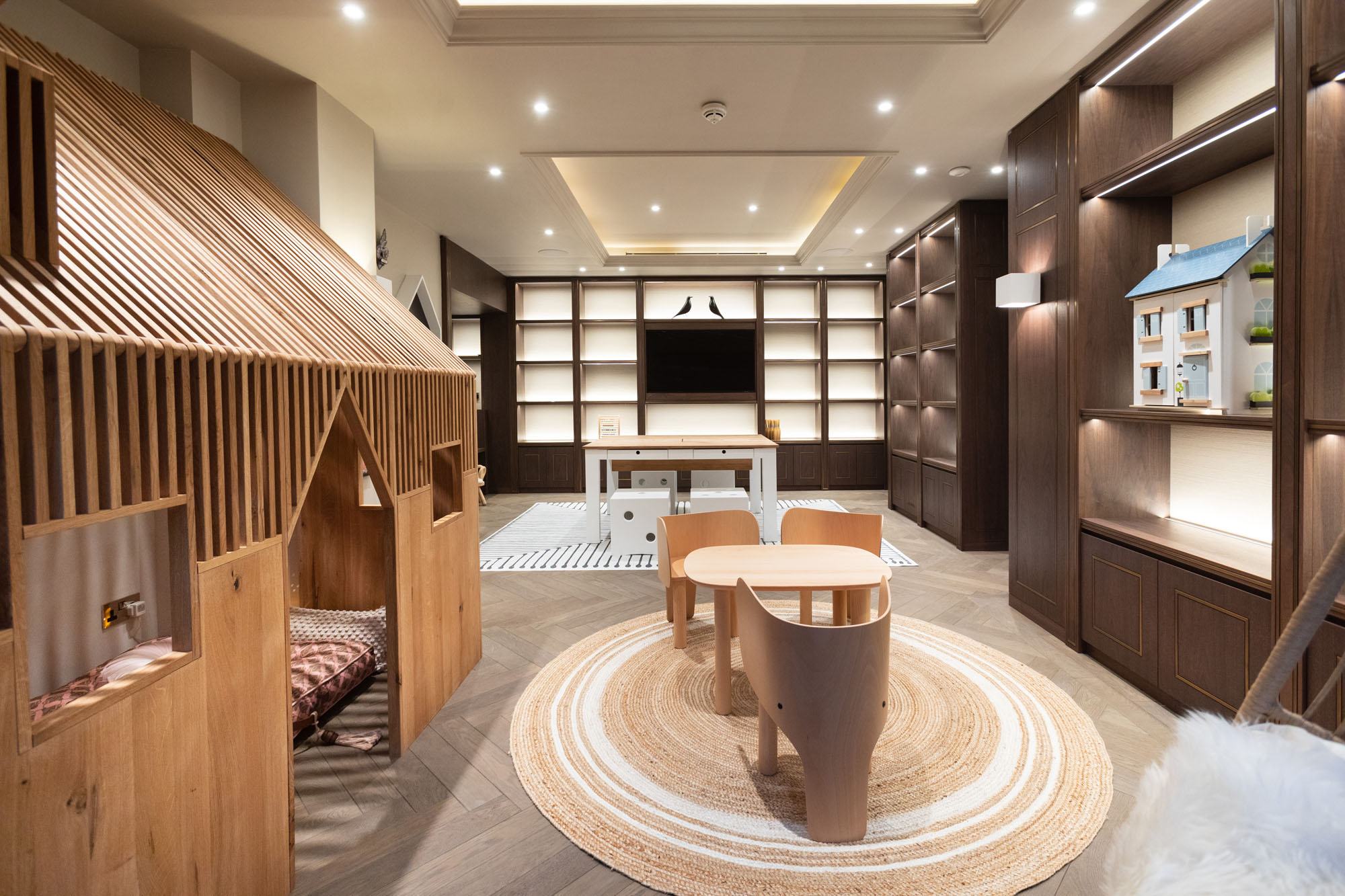Contemporary children’s playroom in Cobham designed by Funky Little Darlings, featuring a whimsical indoor playhouse, play table with EO elephant chairs, a modern craft table with white dice stools and built-in TV and display storage unit. A beautifully zoned space combining playful creativity with functional, high-end kids’ interior design.