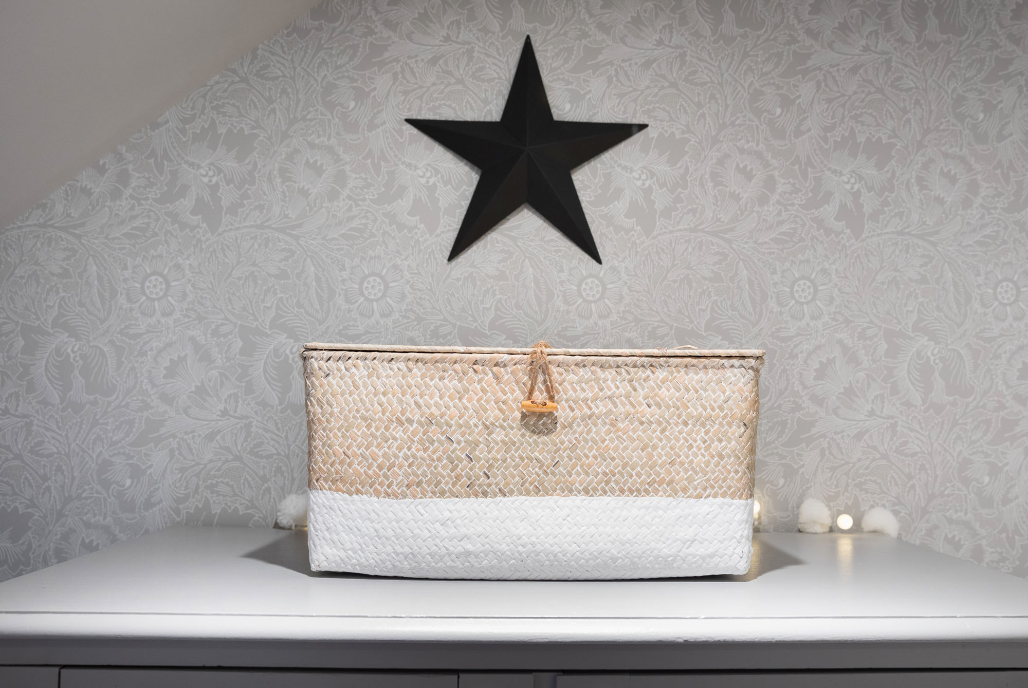Funky Little Darlings Cobham shared triple bedroom with charming vintage storage solutions, including a vintage woven basket box with black tin star styled with pom pom fairy lights and heritage William Morris wallpaper for cosy, designer kids’ storage.