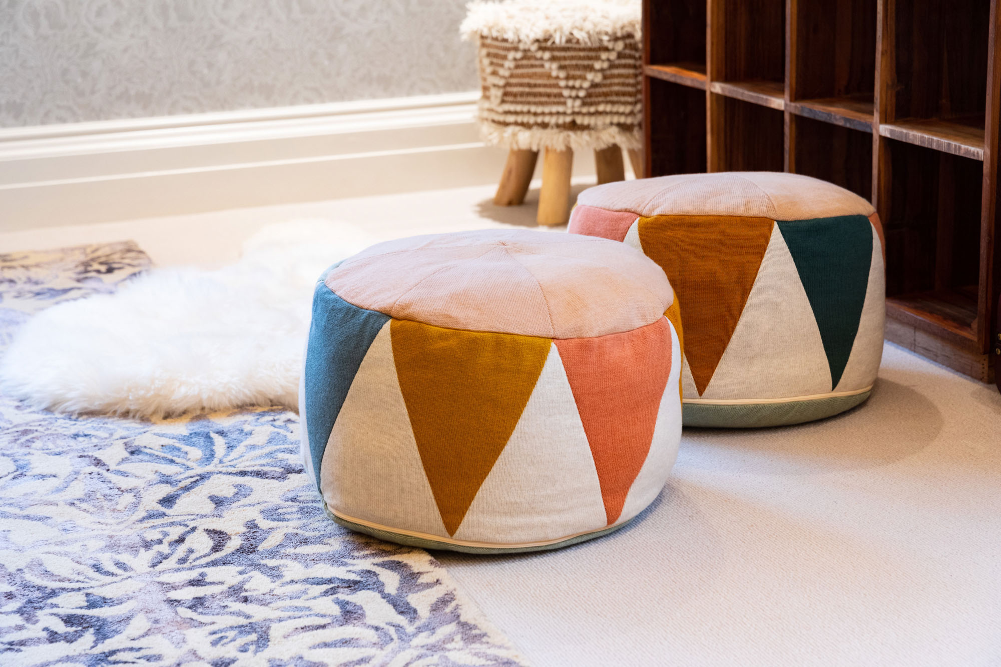 Colourful knitted pouffes, a heritage-inspired William Morris patterned rug and playful yet elegant interior styling designed for comfort and creativity in sibling spaces.