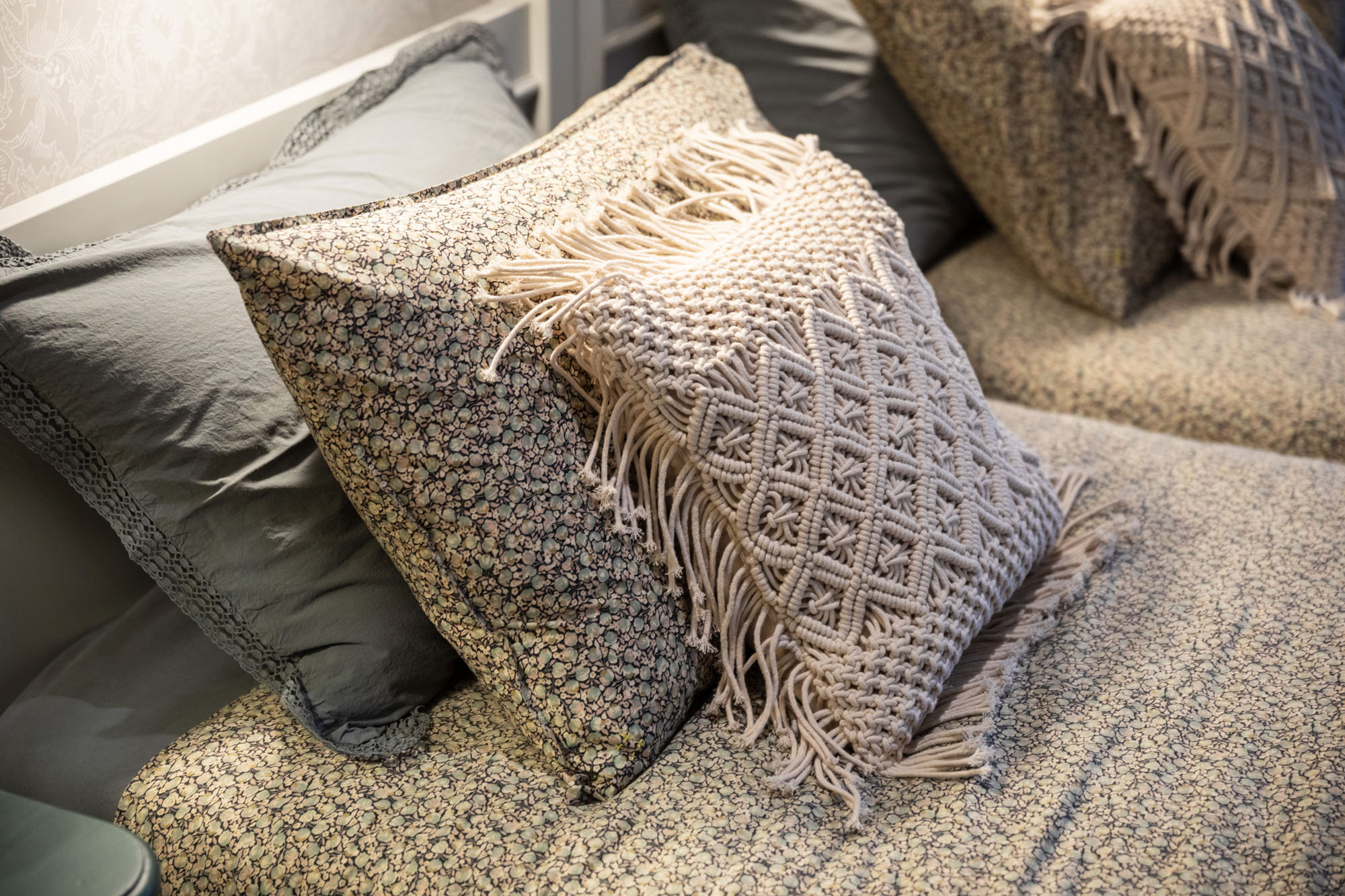 Charming shared triple children's bedroom in Cobham by Funky Little Darlings, showcasing elegantly layered floral bed linen with coordinating textural macrame accent cushions makes for a beautifully styled interior perfect for a whimsical and cosy family space.