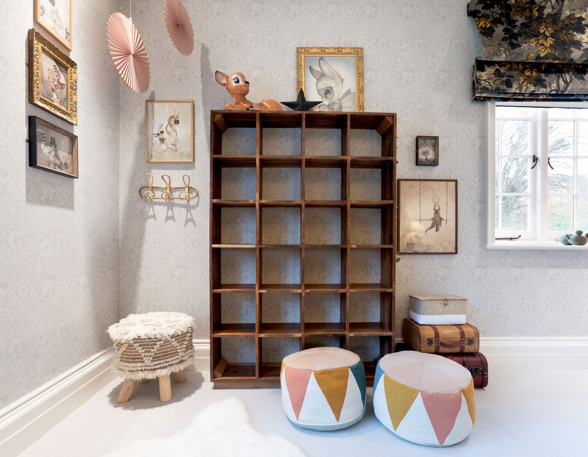 Boho-inspired shared triple children’s bedroom in Cobham designed by Funky Little Darlings, showcasing vintage wooden shelf, cosy pouffe seating, magical fairy lights, a lying fawn lamp and iconic William Morris floral wallpaper evoke a and stylish kids' interior design.