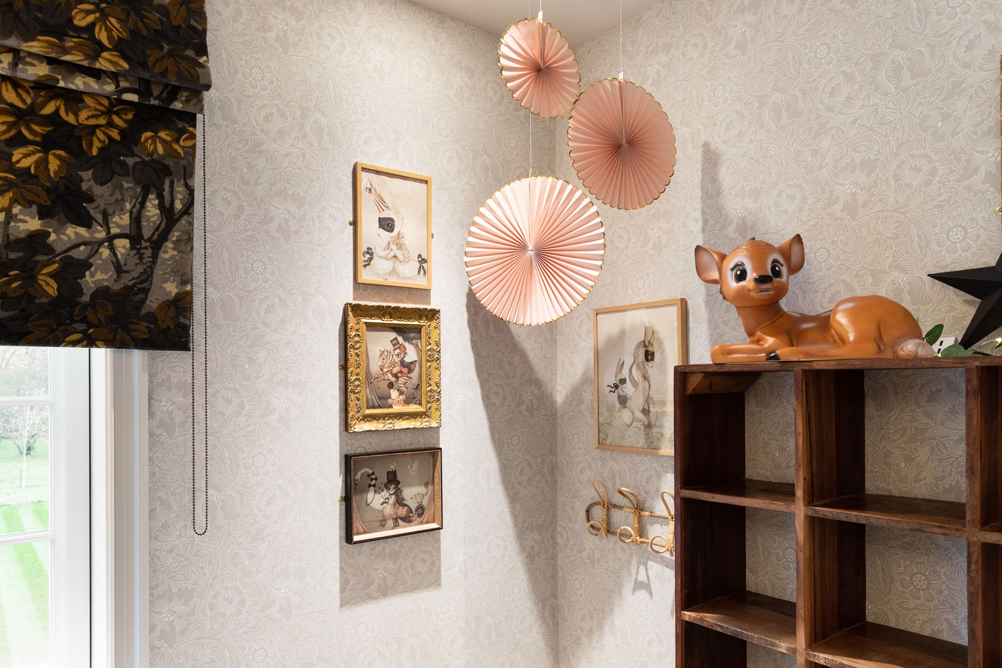 Whimsical shared triple bedroom for children in Cobham, designed by Funky Little Darlings, featuring vintage wooden shelf, evocative art prints, charming lying fawn lamp and timeless William Morris floral wallpaper make for a boho-style kids’ interior with vintage flair.
