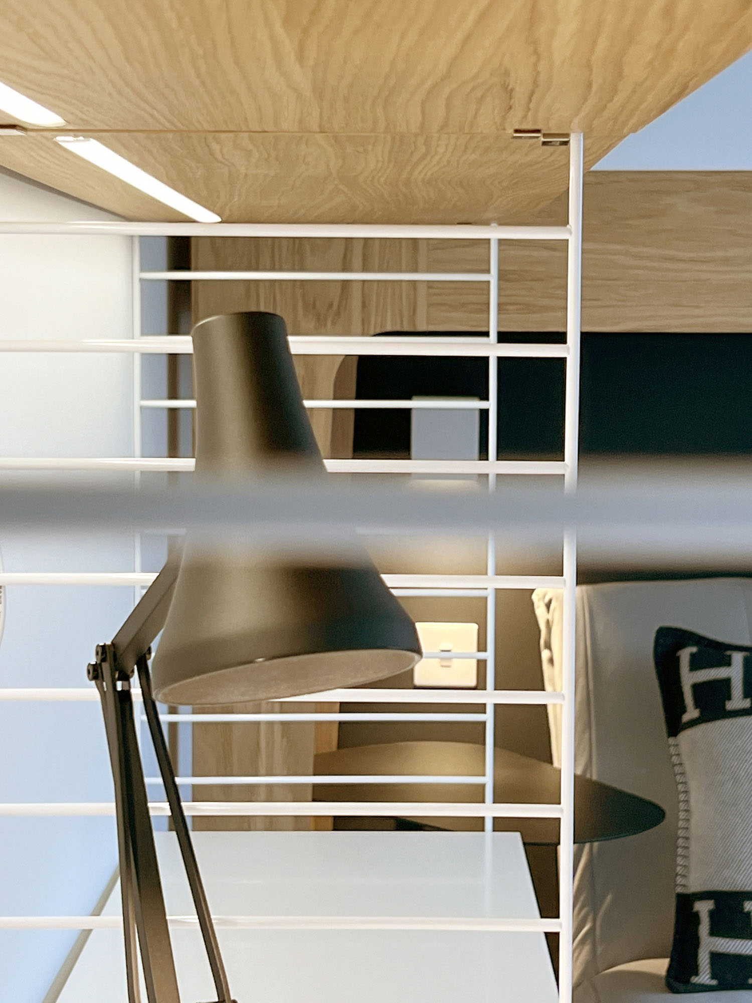 Stylish boys' bedroom in Fulham featuring a String desk and storage system, integrated LED shelf lighting, classic Anglepoise lamp, and a loft bed with modern design elements by Funky Little Darlings.