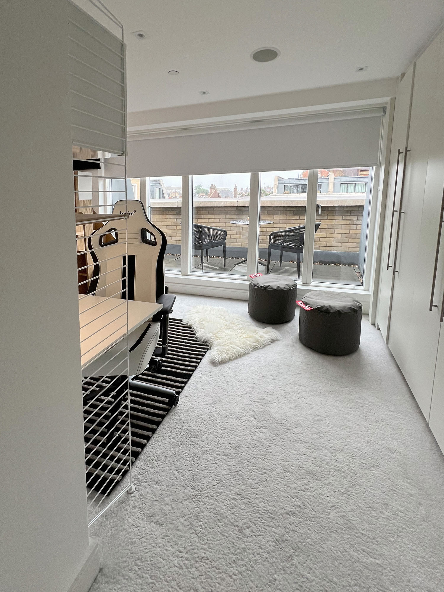 Stylish boys' bedroom in Fulham featuring a String desk and storage system, integrated LED shelf lighting, classic Anglepoise lamp, and a loft bed with modern design elements by Funky Little Darlings.