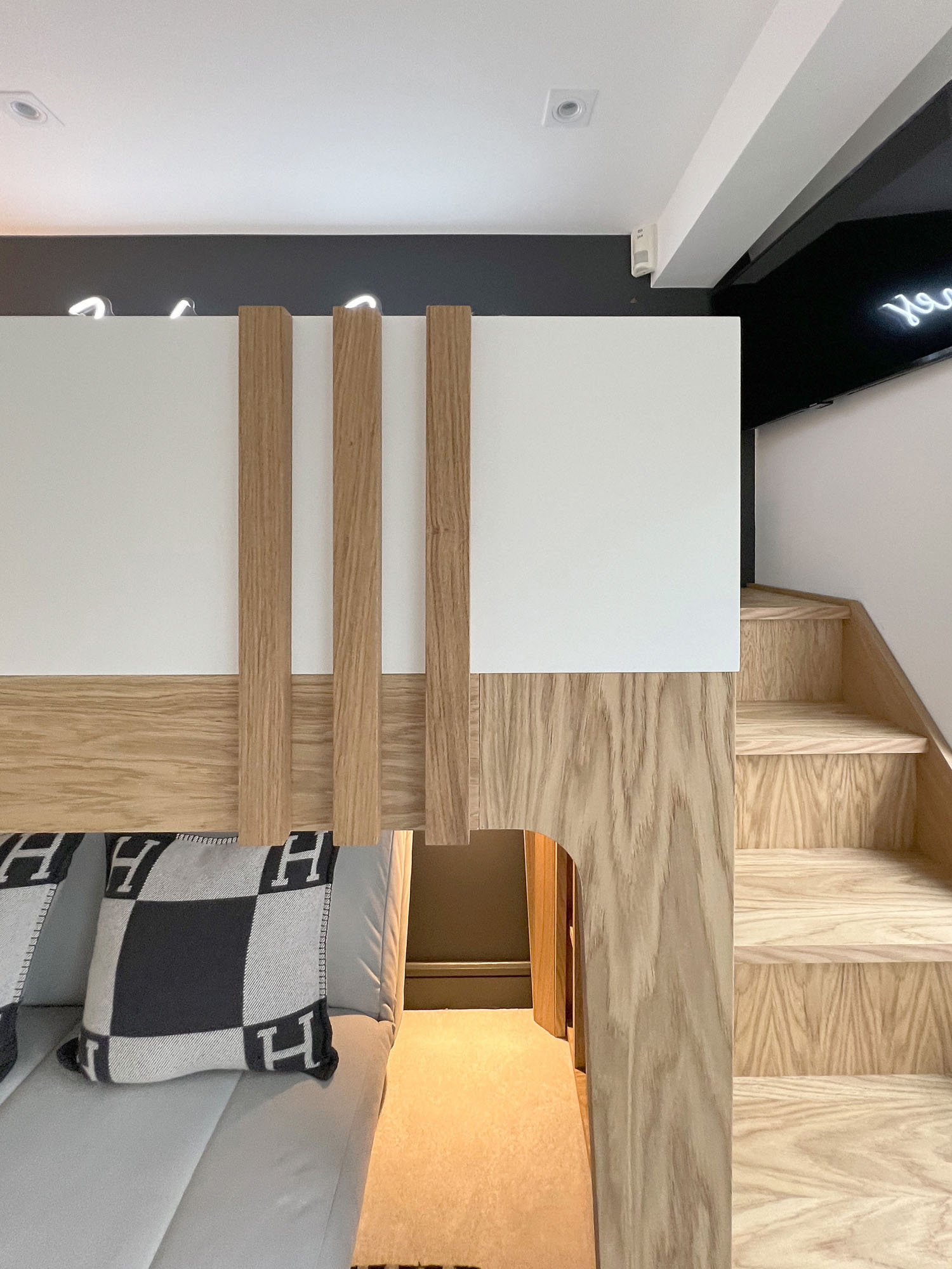 Funky Little Darlings Fulham boys bedroom featuring white bespoke loft bed with oak steps, sofa bed underneath against Neptune Charcoal paint with integrated lighting, and Hermes cushions for stylish comfort.