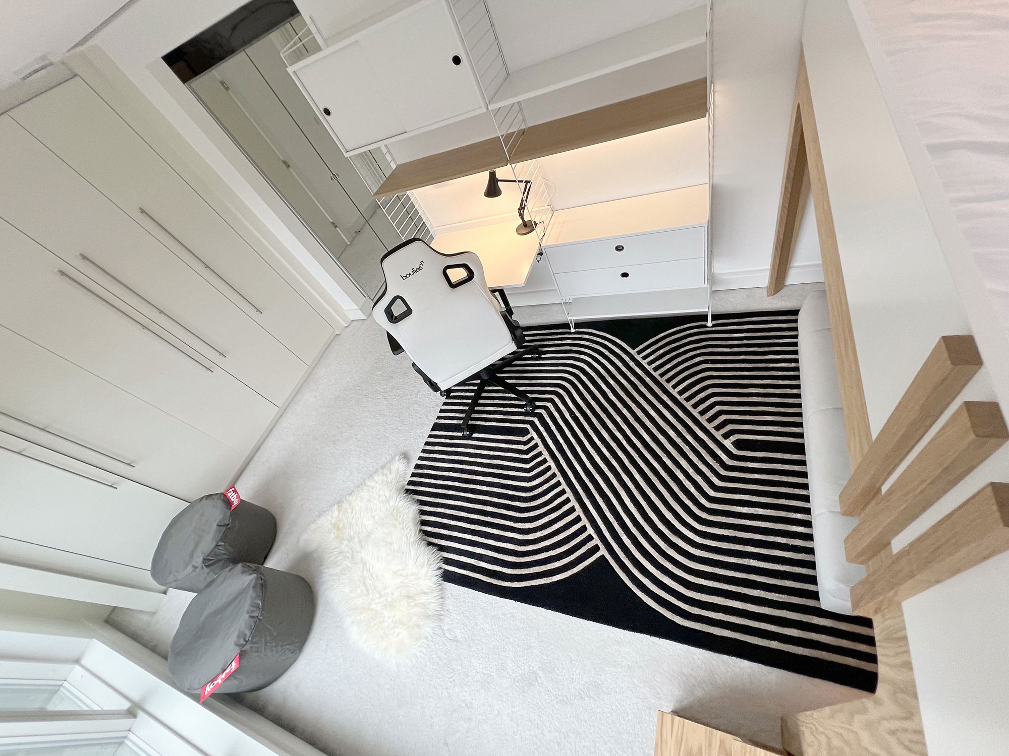 Funky Little Darlings Fulham boys bedroom featuring white bespoke loft bed with oak details, String desk and storage with Anglepoise lamp, Boulies gaming chair, black graphic rug, Fatboy pouffes, sheepskin rug and built-in wardrobe storage.