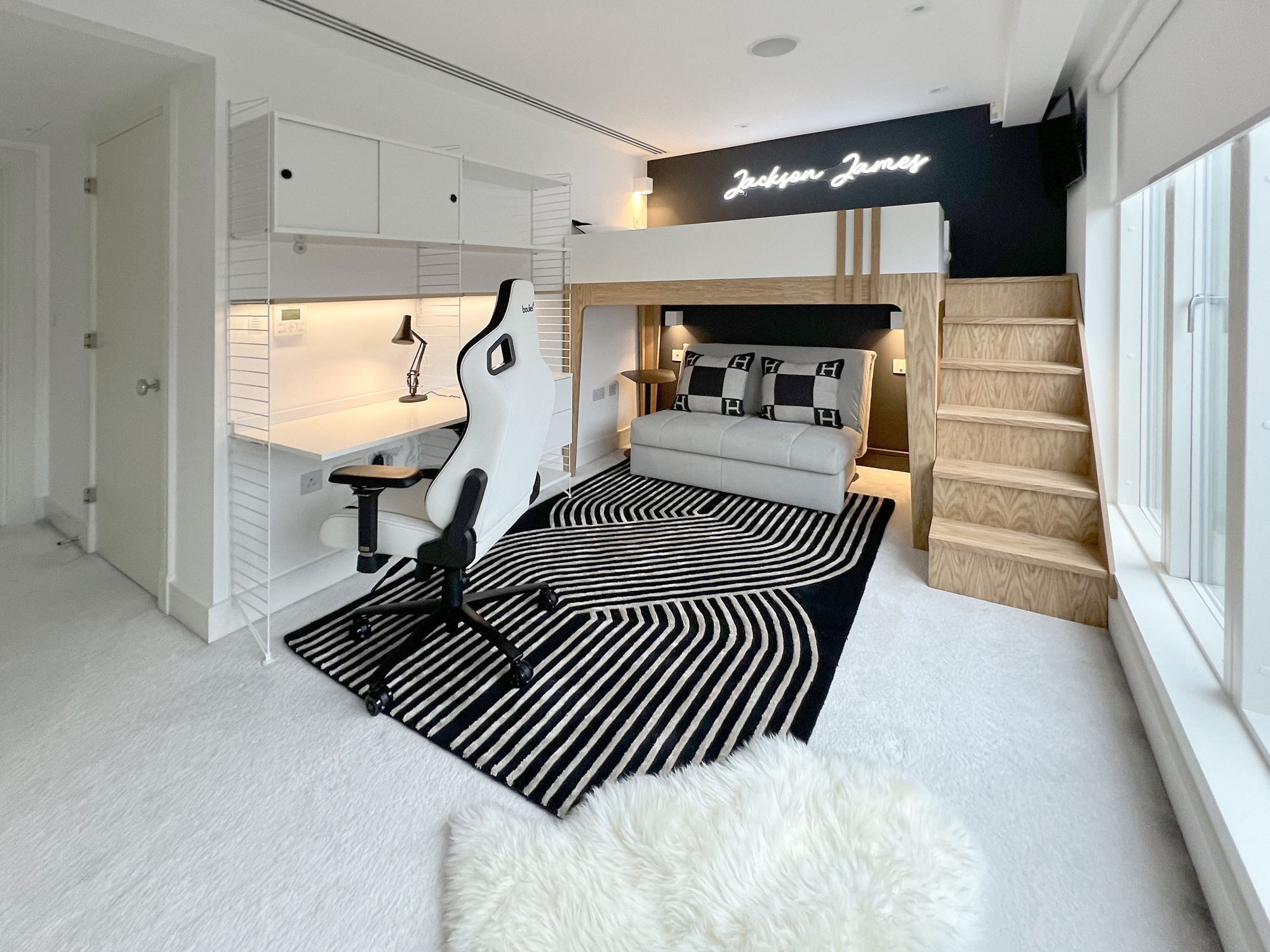 Stylish Fulham boys' bedroom by Funky Little Darlings featuring a custom white bespoke loft bed with oak details, vibrant neon sign, and cosy sofa bed accented with Hermes cushions. This playful yet practical space includes modern wall lights, a mini fridge, String shelving system with desk and storage, a sleek gaming chair, and a bold black graphic rug, perfect for a design-forward, teen-friendly interior.