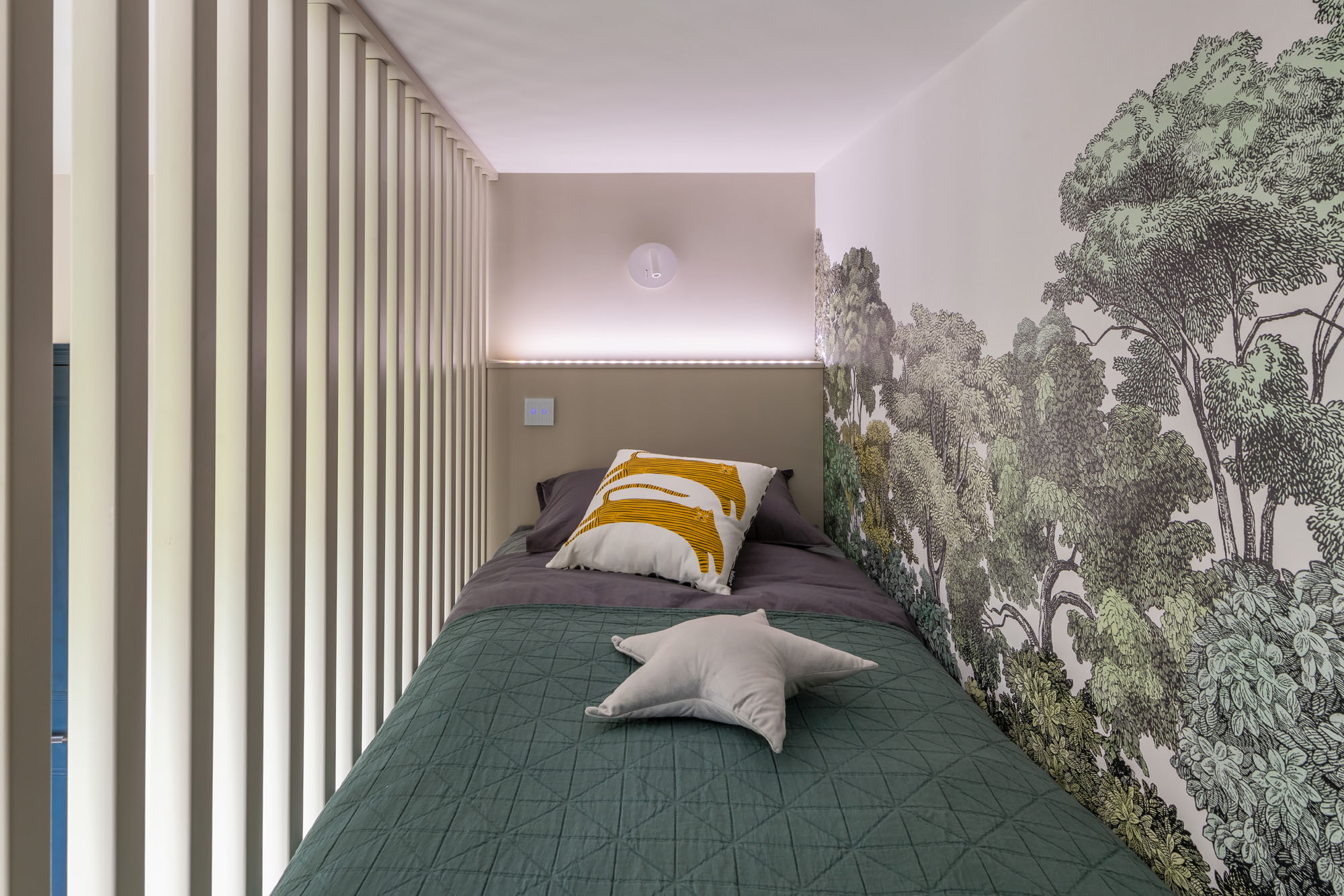 Elegant Hampstead boy’s bedroom by Funky Little Darlings, featuring a raised cabin bed with walnut detailing and a verdant Rebel Walls Bellewood forest mural, creating a cozy, nature-inspired sleeping area.