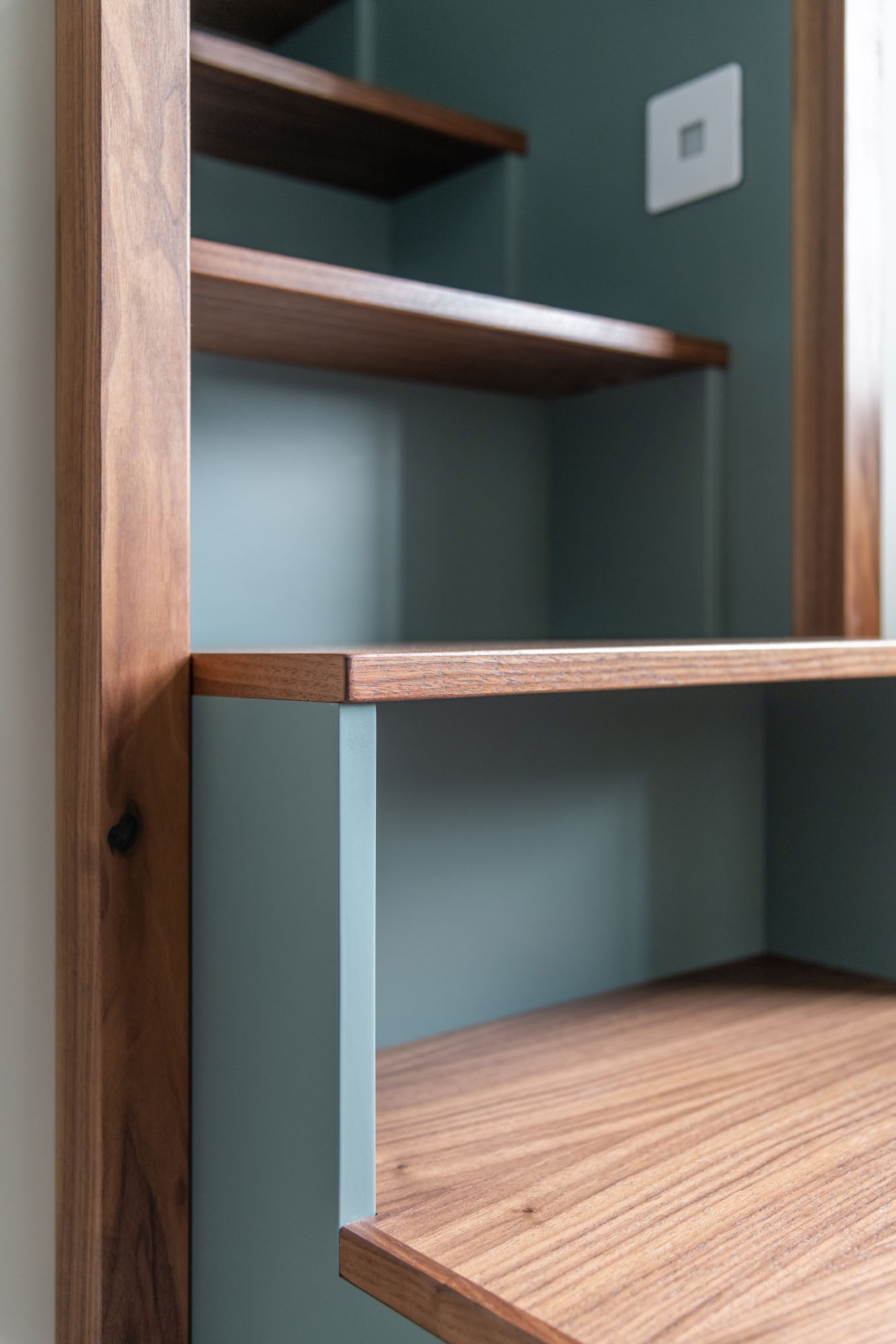 Stylish boy's bedroom in Hampstead featuring a raised walnut cabin bed with built-in book storage steps painted in Little Greene’s Livid green, designed by Funky Little Darlings for modern functionality and playful sophistication.