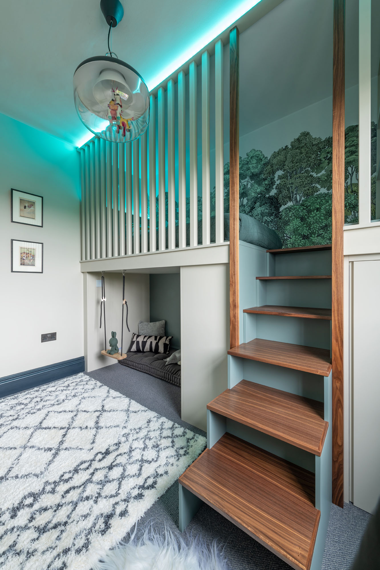 Creative Hampstead boy’s bedroom designed by Funky Little Darlings, featuring a raised cabin bed with blue LED colour-change lighting, built-in storage steps, a cosy reading nook underneath the bed with a playful swing, soft seating and book storage along with a soft rug for a fun, sensory-rich space.