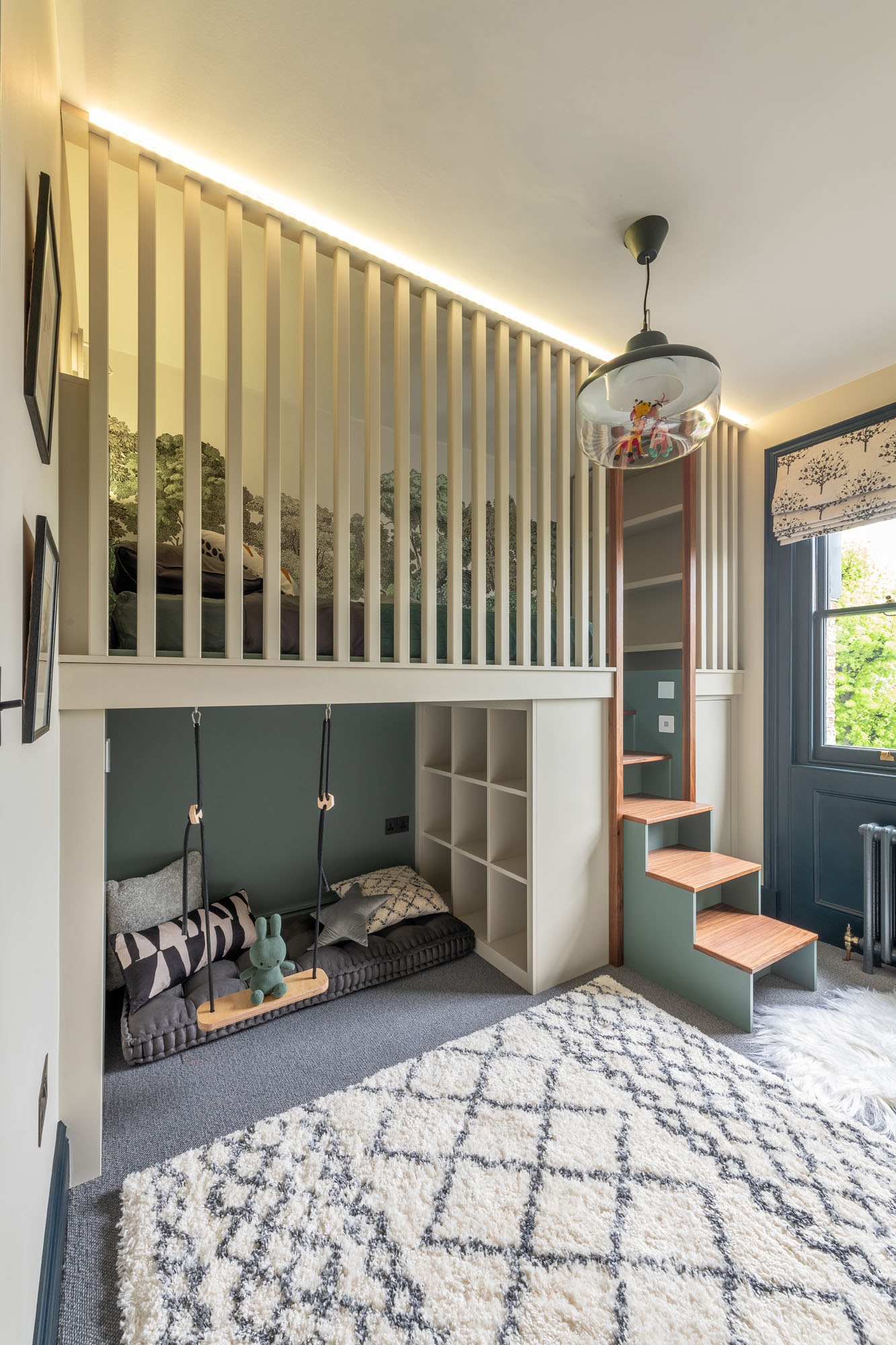 Creative Hampstead boy’s bedroom designed by Funky Little Darlings, featuring a raised cabin bed with yellow LED colour-change lighting, built-in storage steps, a cosy reading nook underneath the bed with a playful swing, soft seating and book storage along with a soft rug for a fun, sensory-rich space.