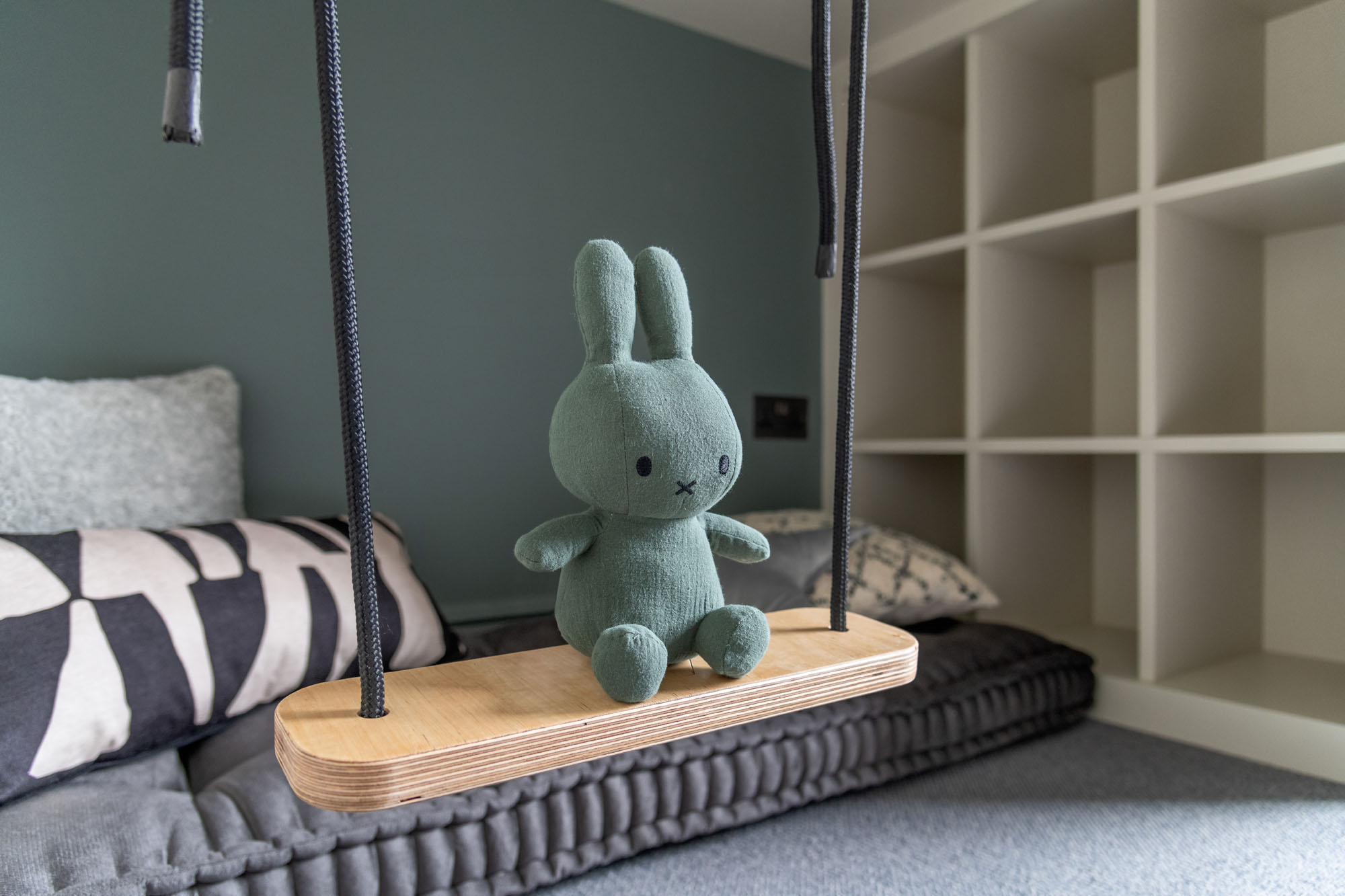 Stylish boys’ bedroom in Hampstead by Funky Little Darlings featuring a modern cabin bed with an under-bed chill-out play area, built-in bookshelves, smart storage solutions, a playful indoor swing with Miffy bunny sitting on swing for a humorous touch.