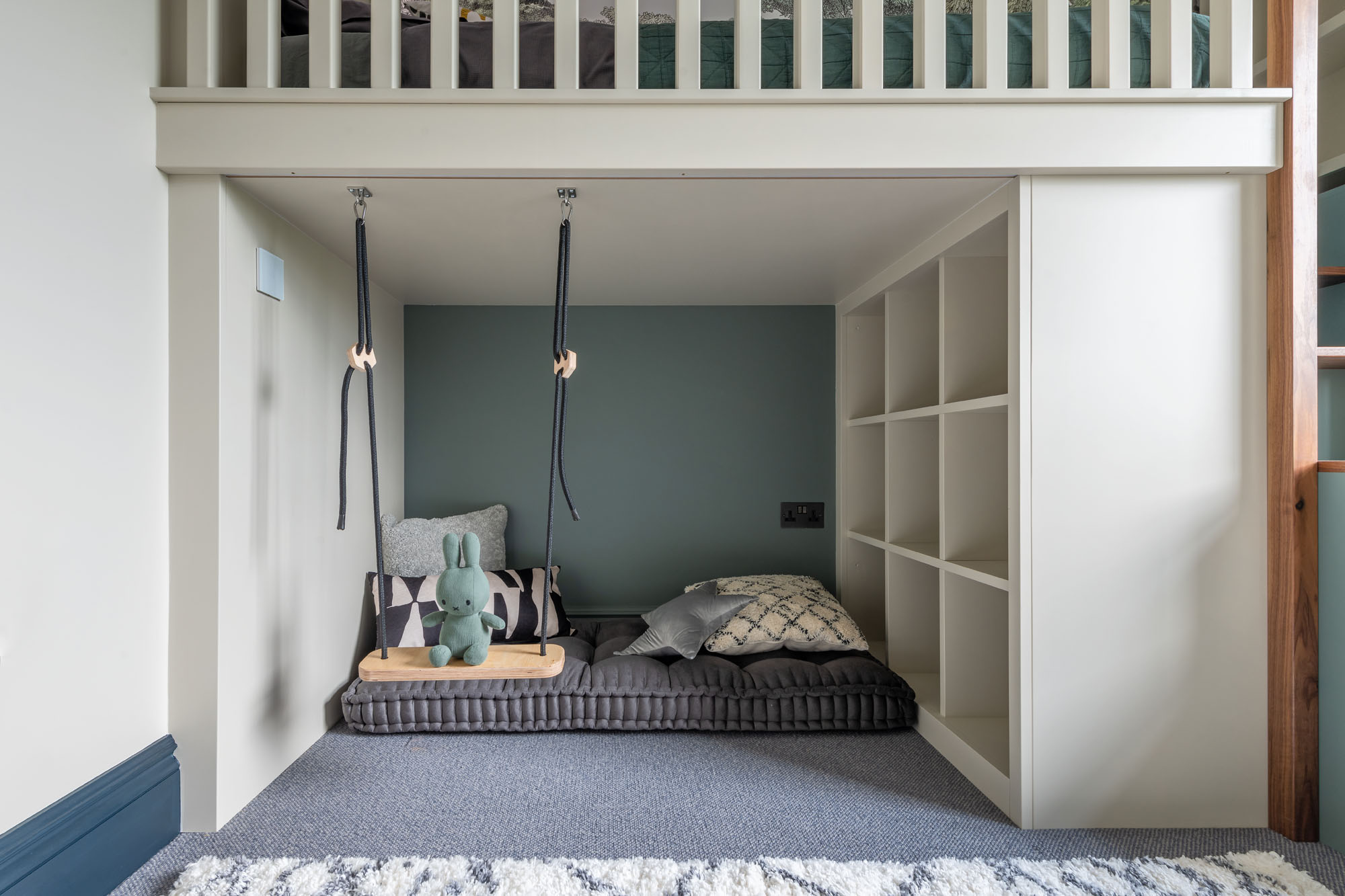 Stylish boys’ bedroom in Hampstead by Funky Little Darlings featuring a modern cabin bed with an under-bed chill-out play area and soft seating, built-in bookshelves, smart storage solutions, a playful indoor swing with Miffy bunny sitting on swing for a humorous touch.