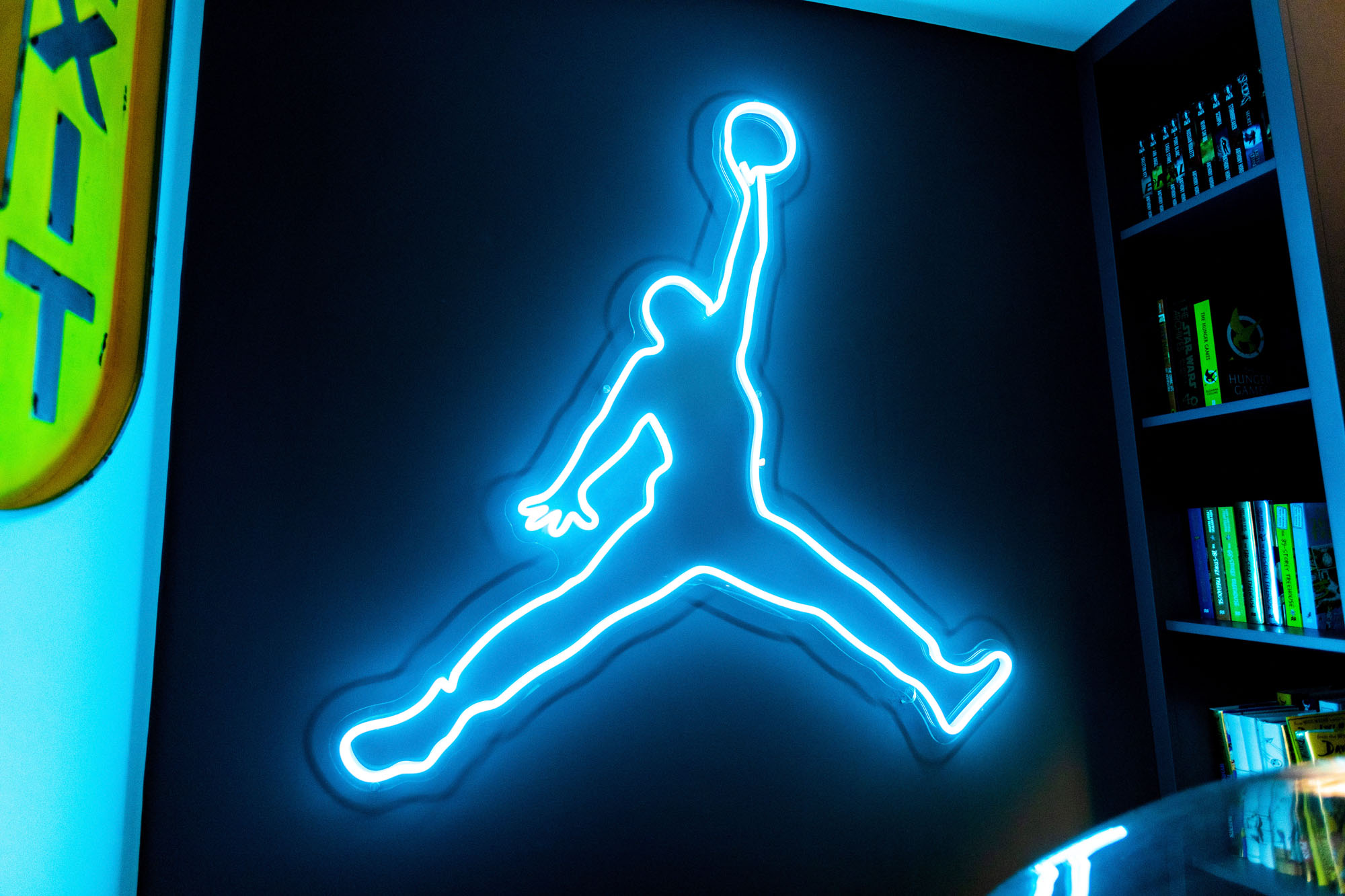 Contemporary Hampstead boy’s bedroom designed by Funky Little Darlings featuring vibrant bespoke turquoise Michael Jordan neon sign illumination hidden book storage adding a bold and playful focal point to the stylish children’s room interior.