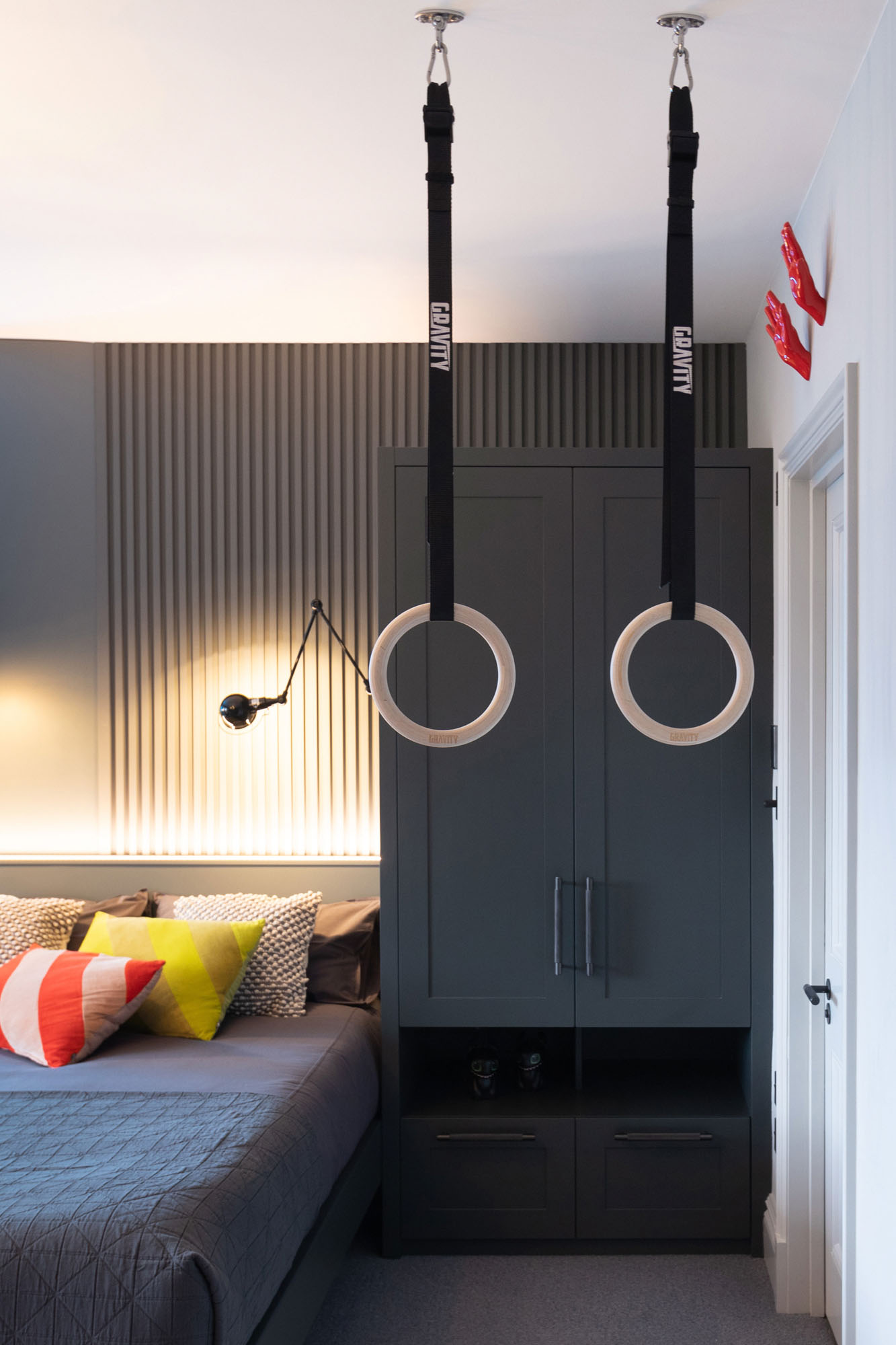 Contemporary Hampstead boy’s bedroom designed by Funky Little Darlings, featuring a bespoke bed with integrated wardrobes, ceiling-mounted fitness rings, slatted wall panelling, vibrant Michael Jordan neon sign, clear hanging bubble chair and industrial Jielde Signal wall lights, blending playful elements with stylish, design-led interiors.