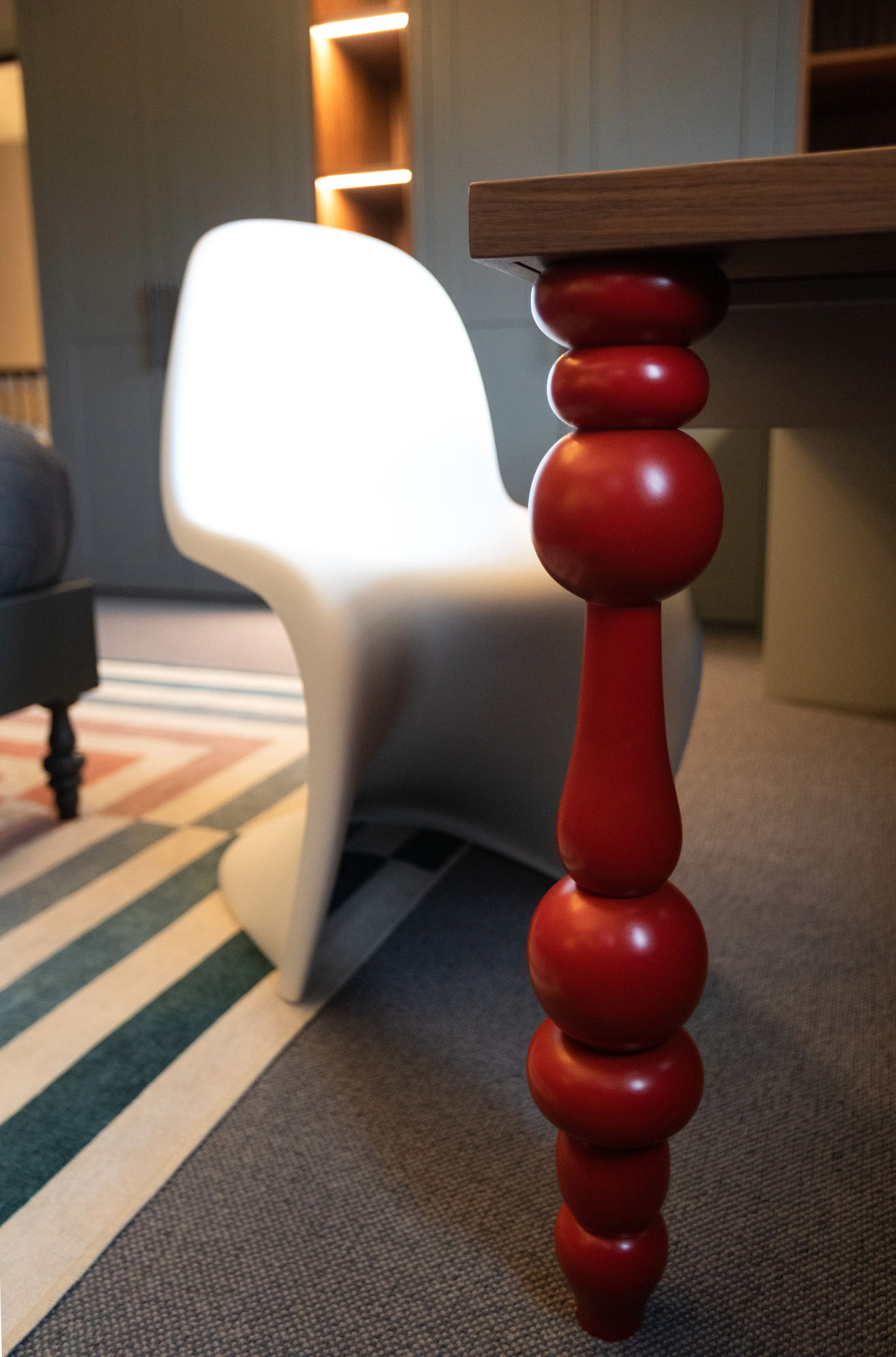 Beautifully designed Hampstead boy’s bedroom by Funky Little Darlings, featuring a bespoke walnut study desk with red ornate turned leg and white Panton chair set against bespoke grey and walnut wardrobe cabinetry and Jonathan Adler rug creating a modern palette for a stylish, functional and child-friendly space.
