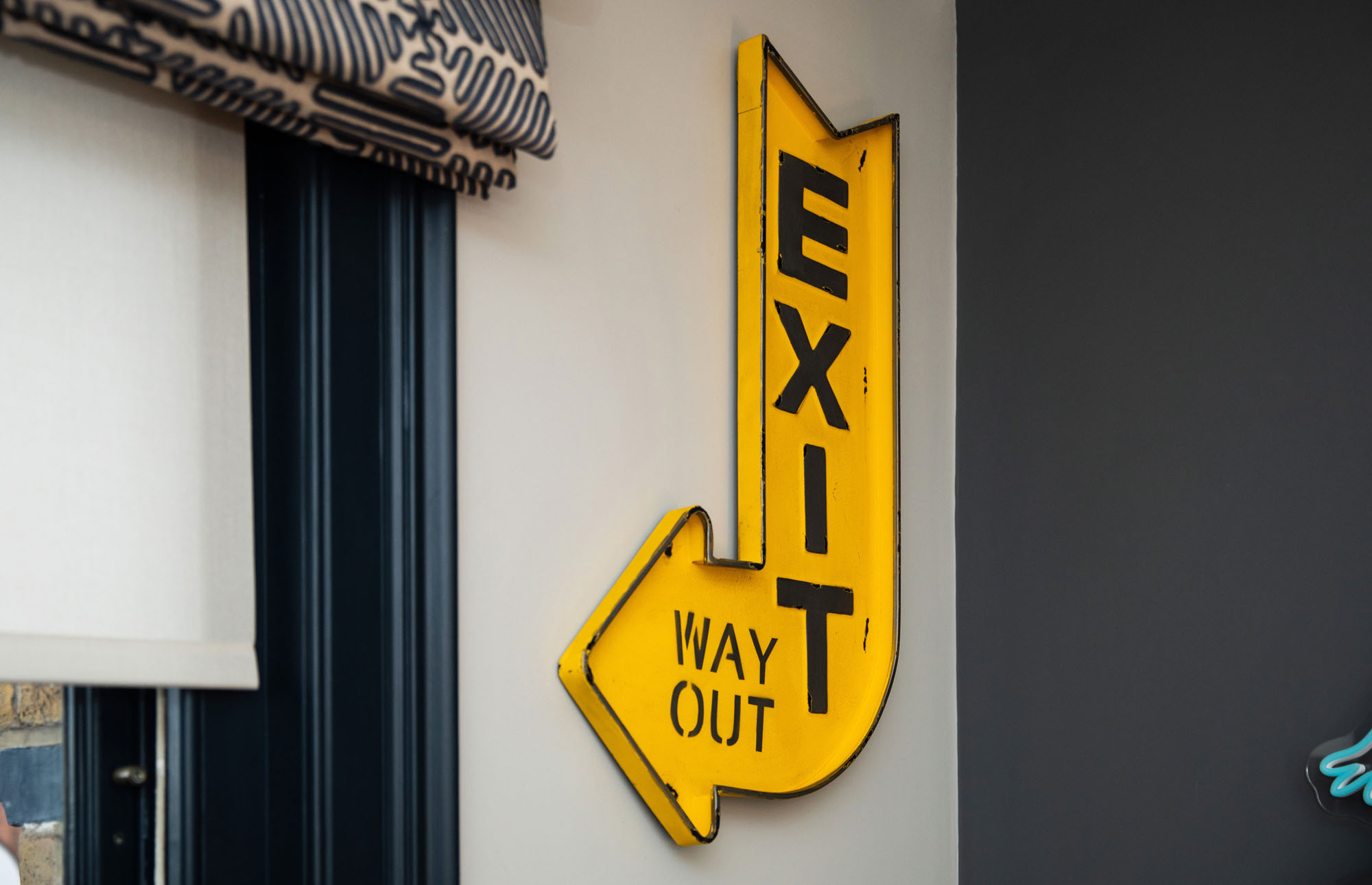 Playful Hampstead boy’s bedroom designed by Funky Little Darlings, featuring a bold yellow “Exit Way Out” wall sign pointing to the window as a quirky focal point, paired with modern children’s décor to create a fun, imaginative, and stylish interior.